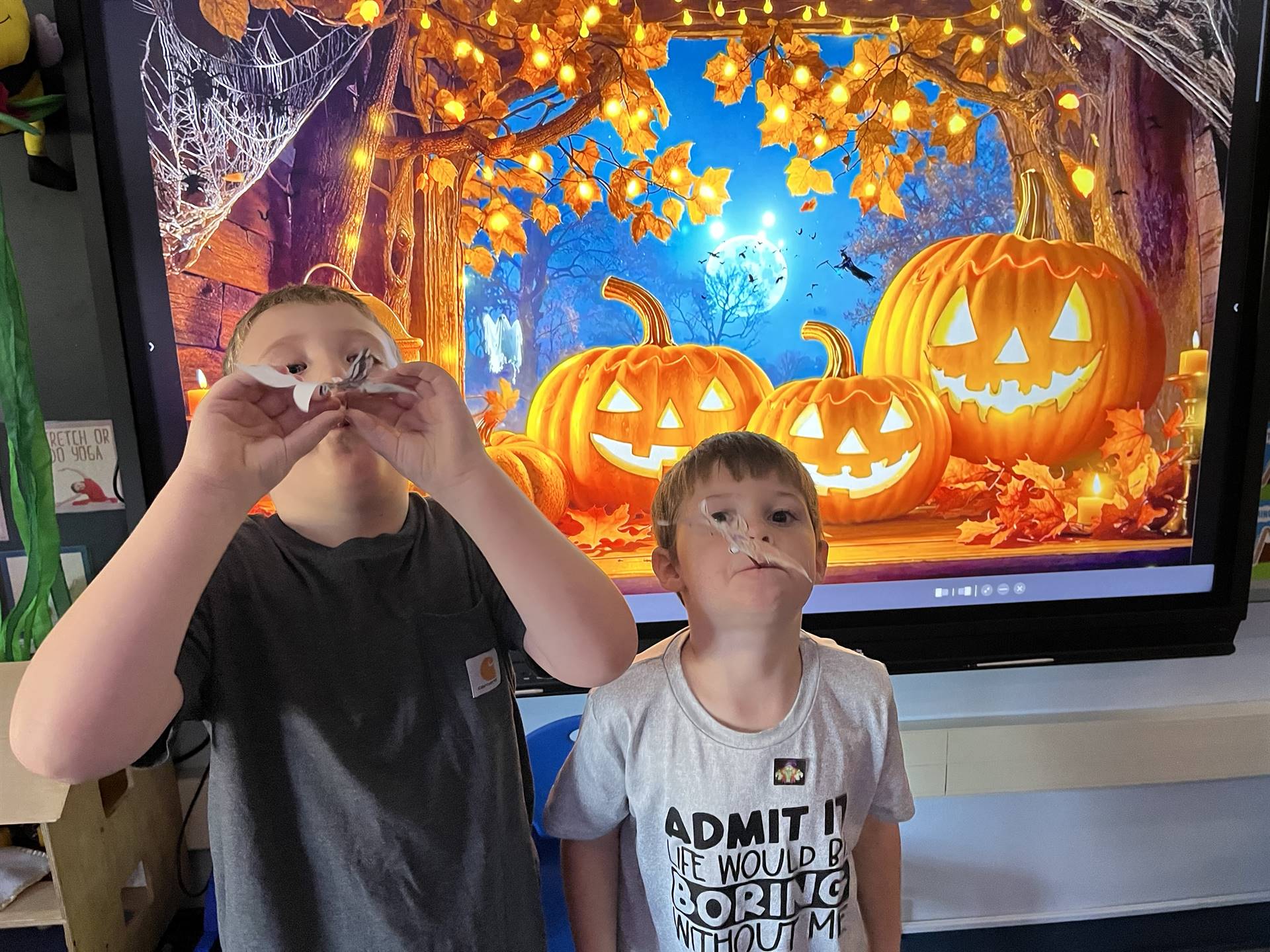 2 students getting ready to blow a paper bat in the air.
