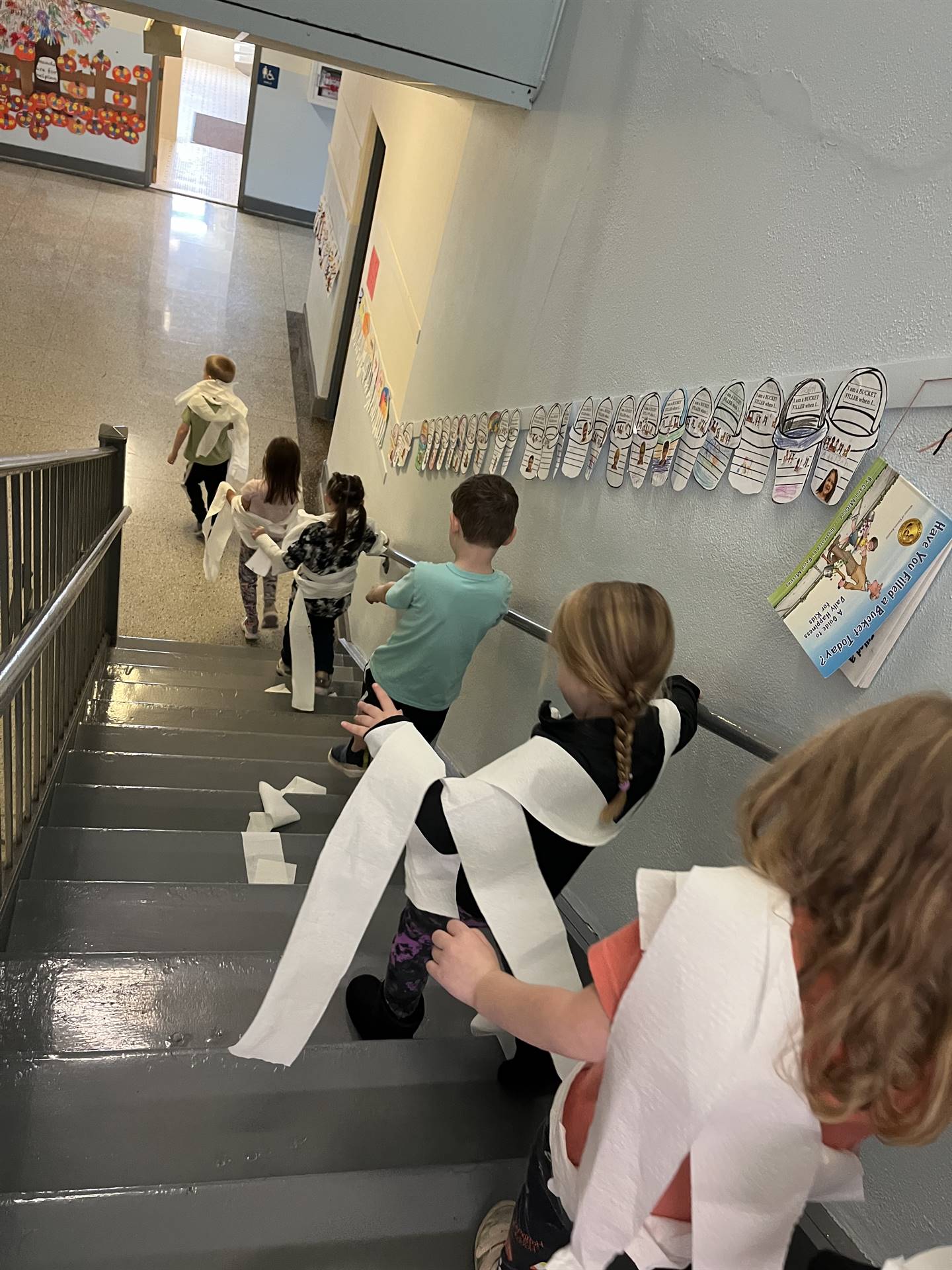 kids wrapped in toilet paper descending stairs