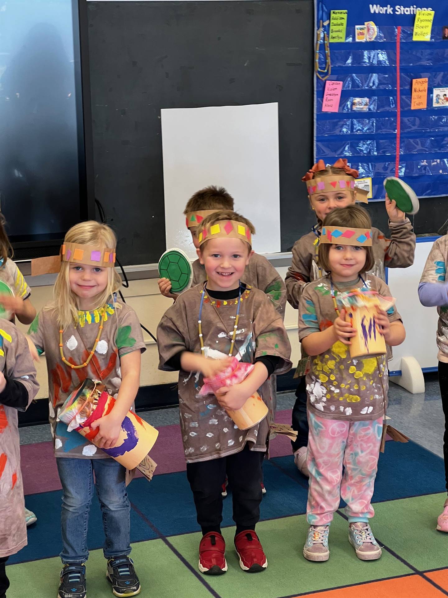 children dressed as native americans and beating on homemade drums.