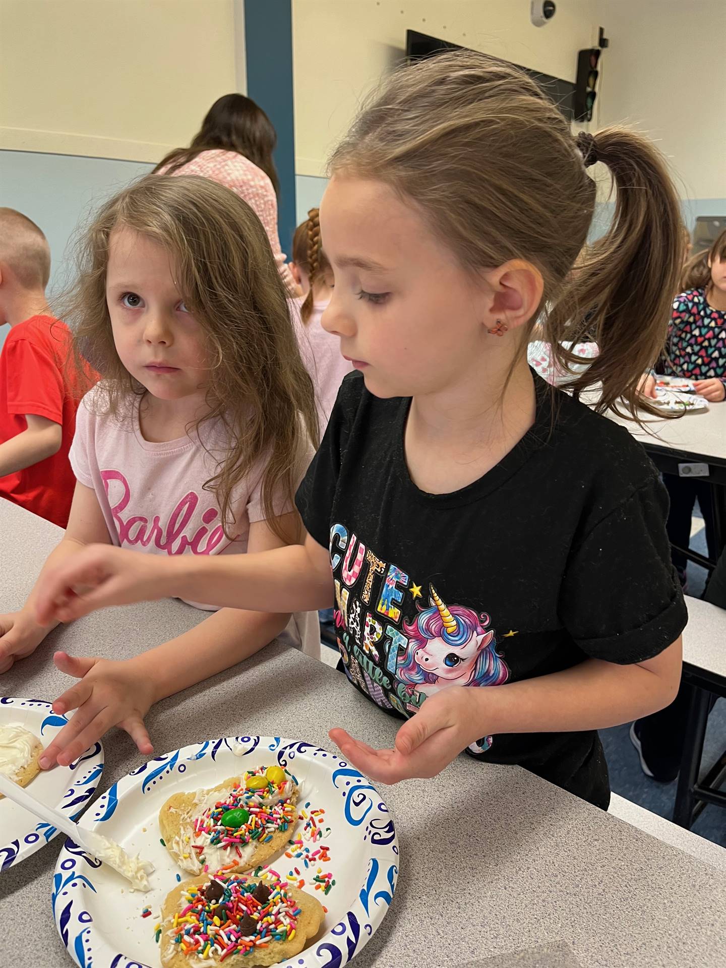 students decorating sugar cookie with icing and candy