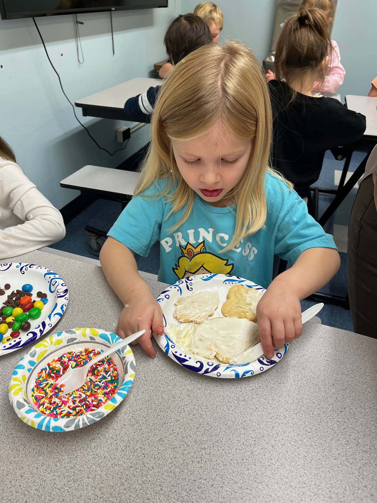student decorating sugar cookie with icing and candy