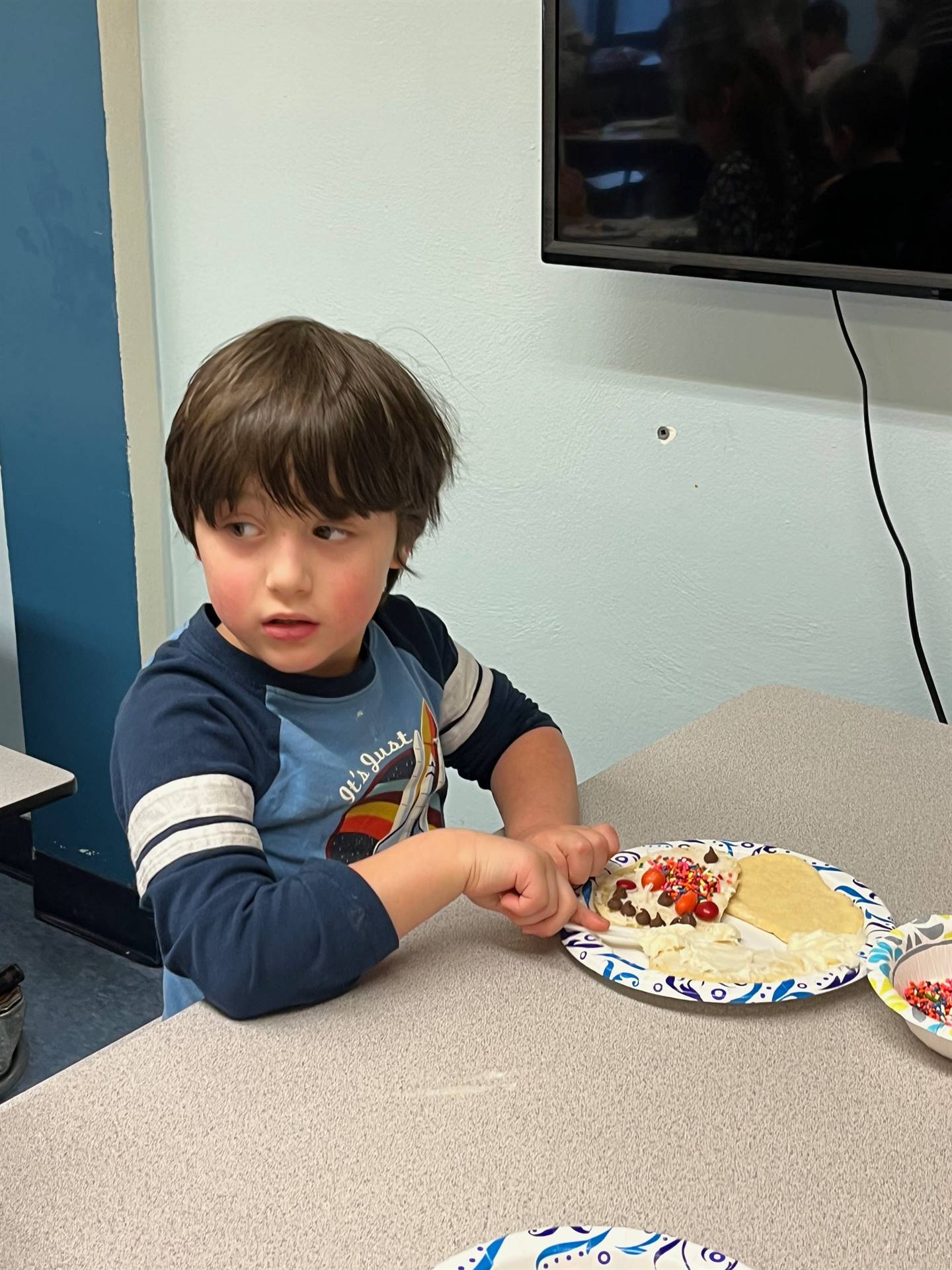 student decorating sugar cookie with icing and candy