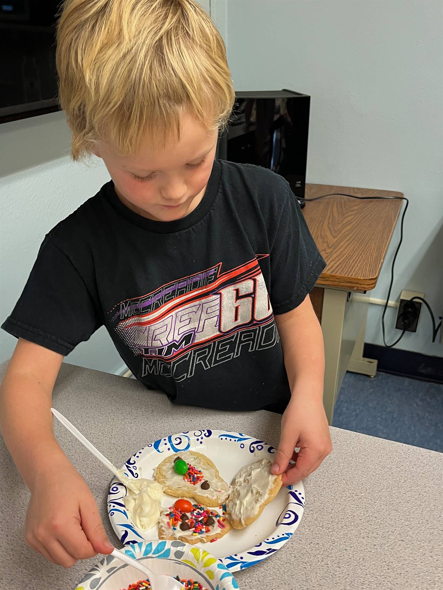 student decorating sugar cookie with icing and candy