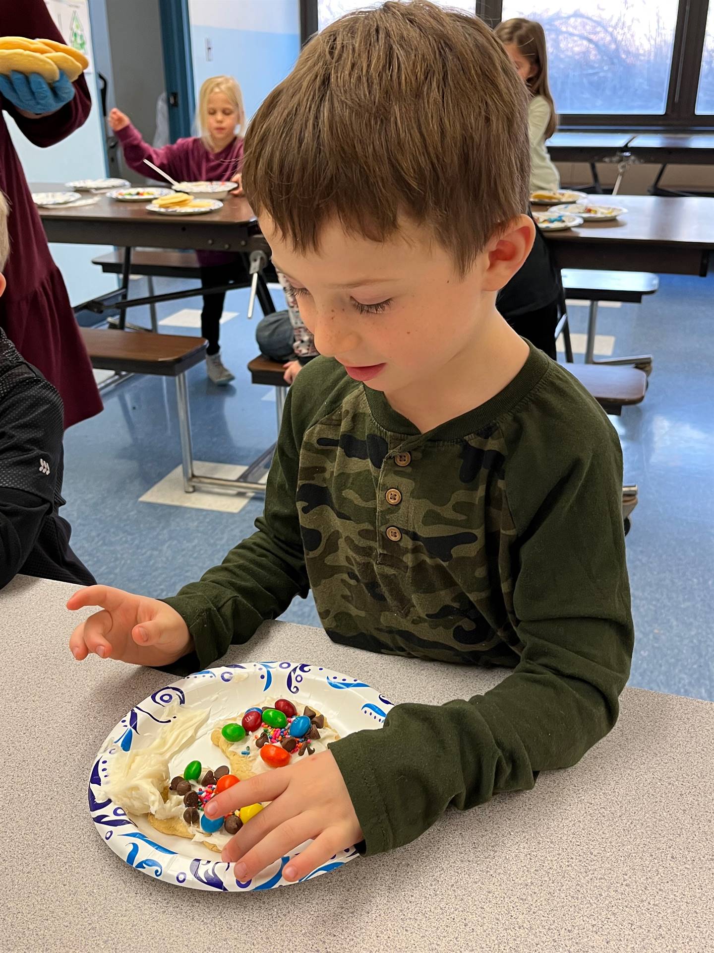 student decorating sugar cookie with icing and candy