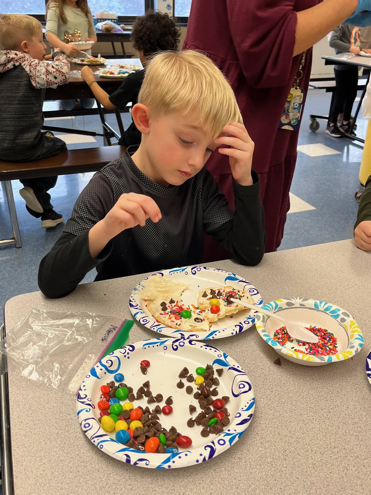 student decorating sugar cookie with icing and candy