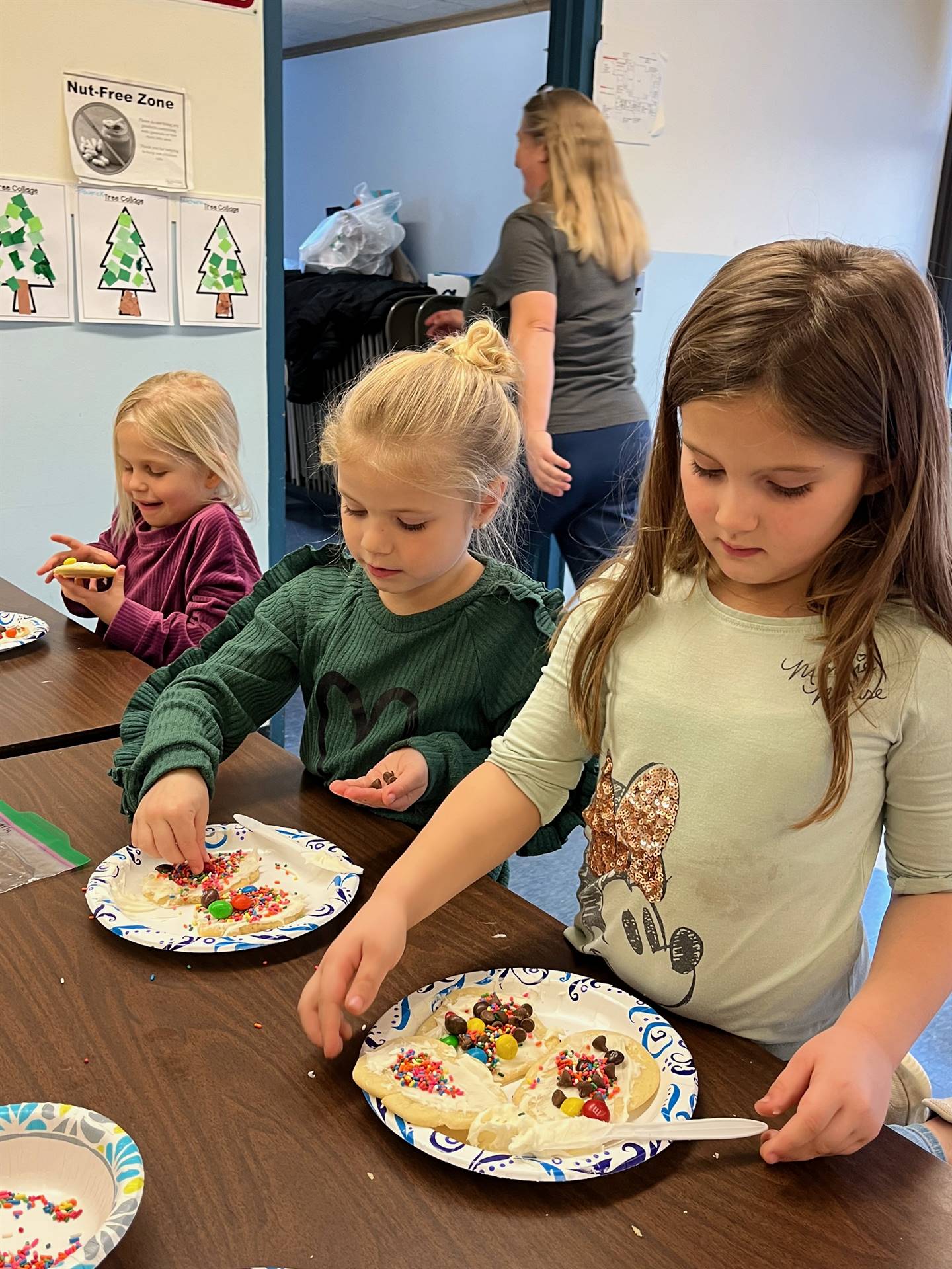 students decorating sugar cookie with icing and candy
