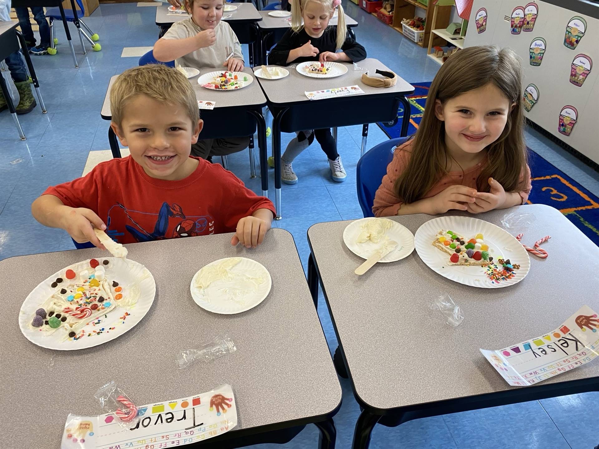 2 students with decorated gingerbread houses.