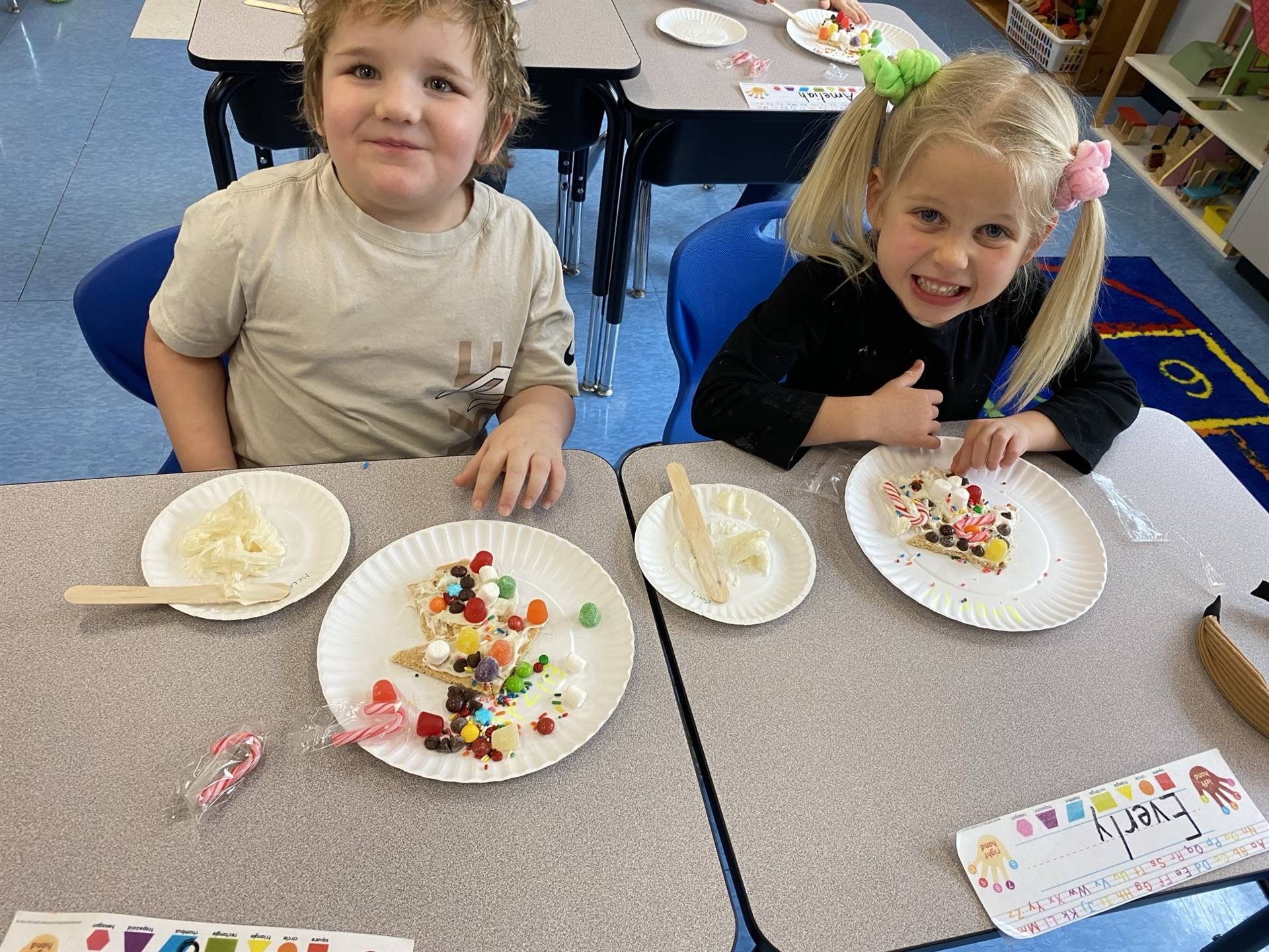 2 students with decorated gingerbread houses.