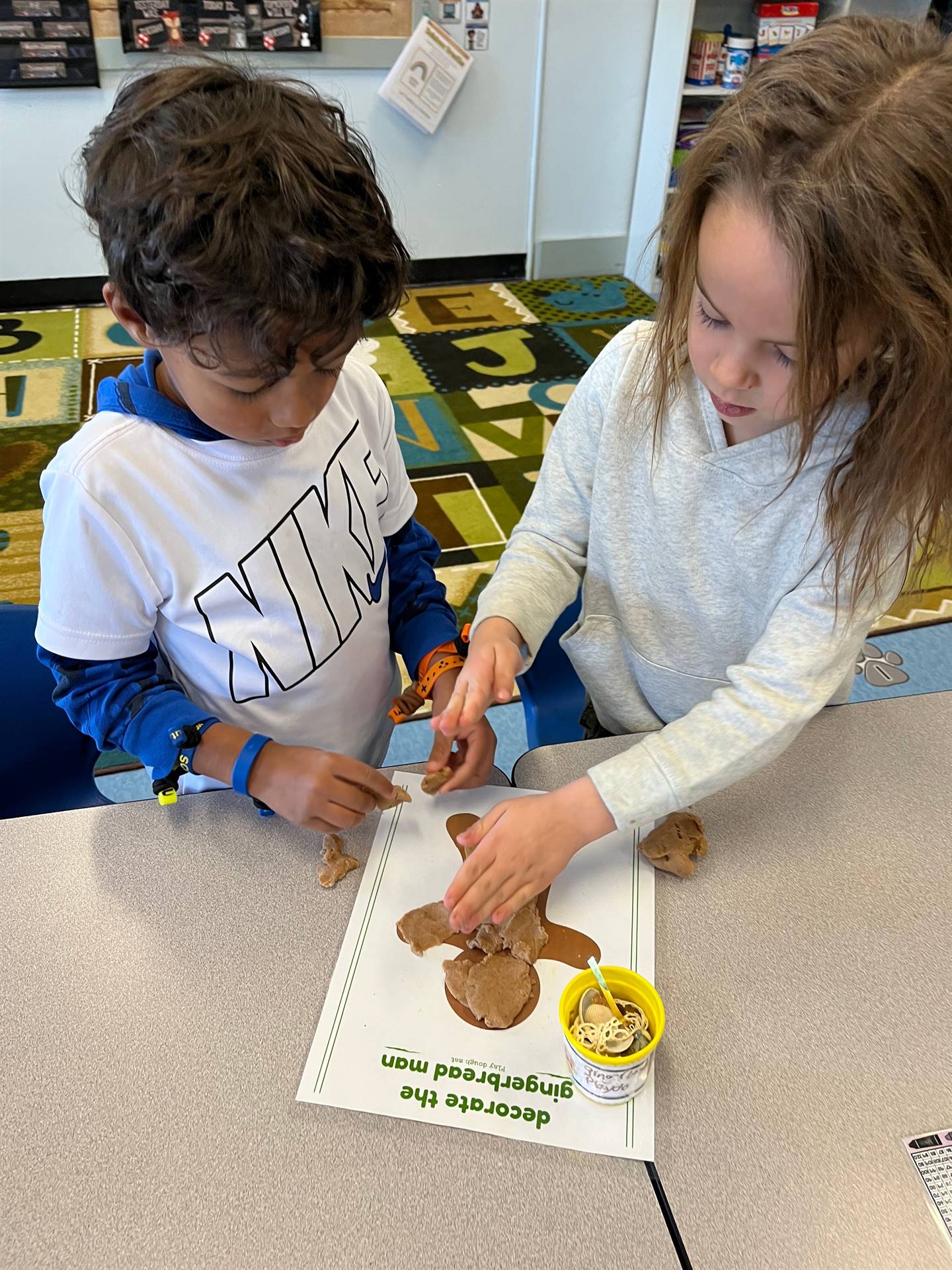 2 students working together to create a play do ginger bread friend.