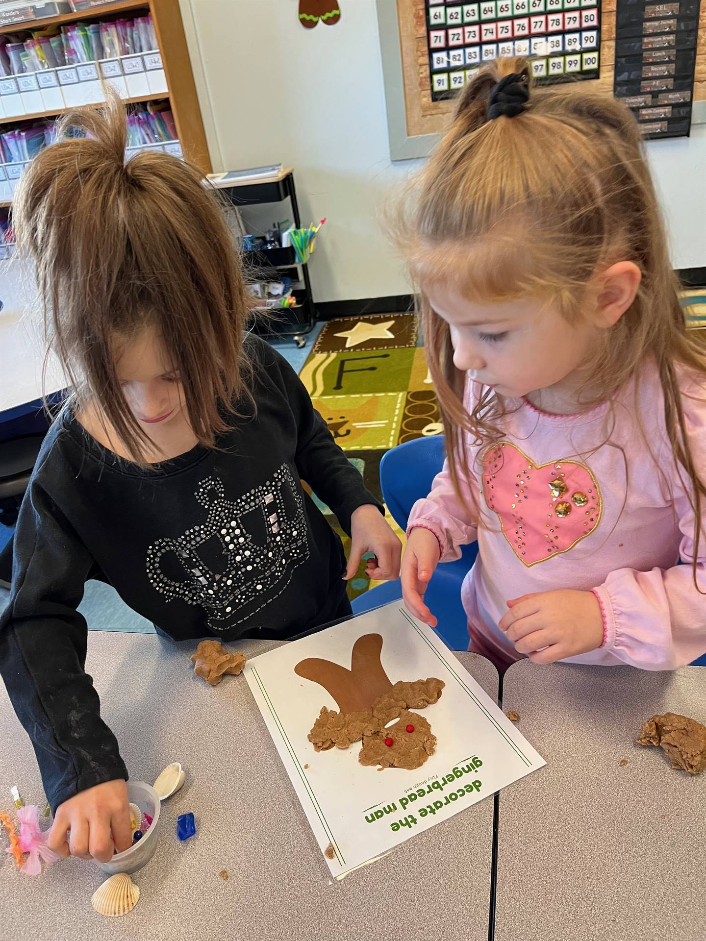 2 students working together to create a play do ginger bread friend.