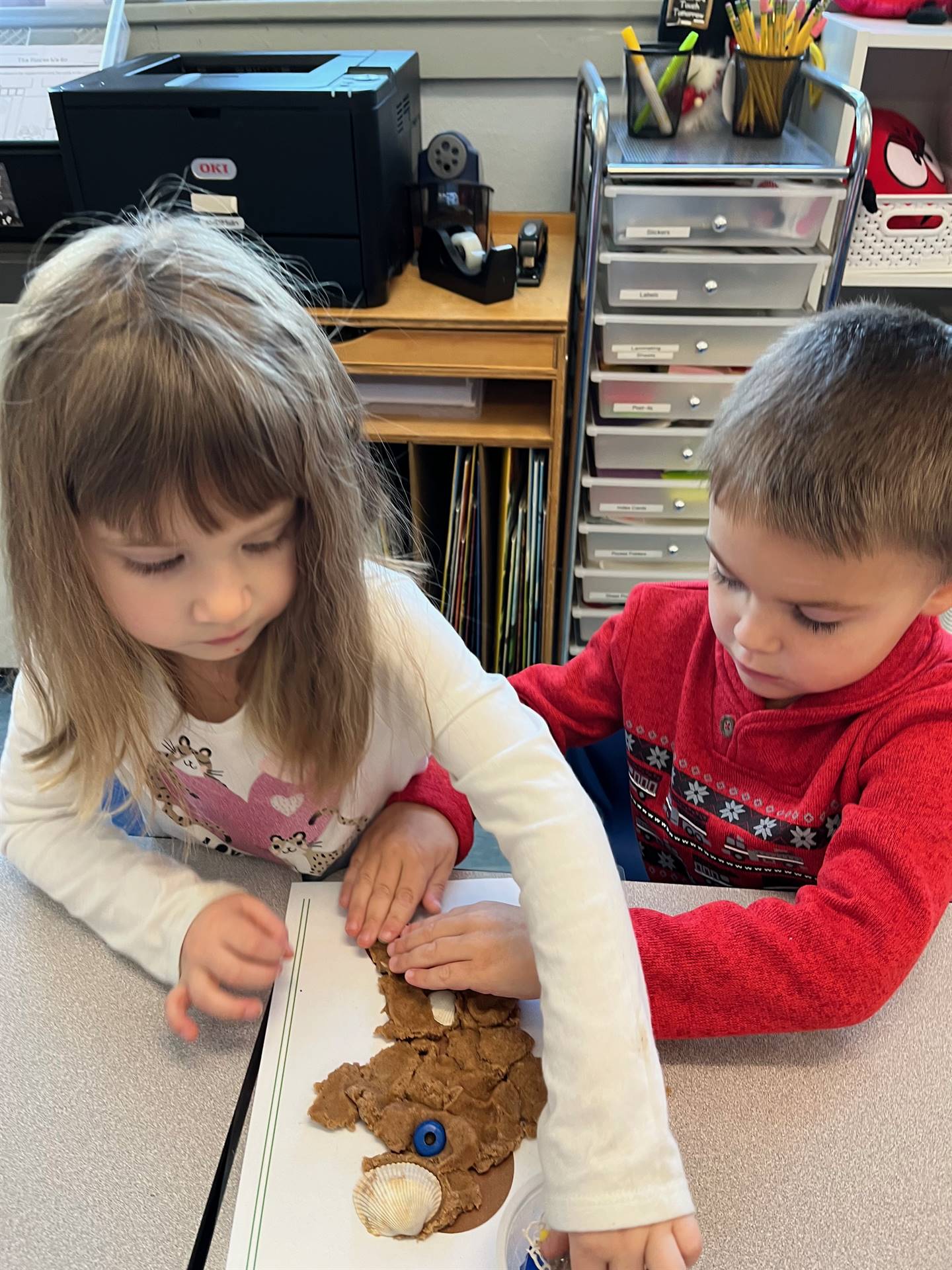 2 students working together to create a play do ginger bread friend.