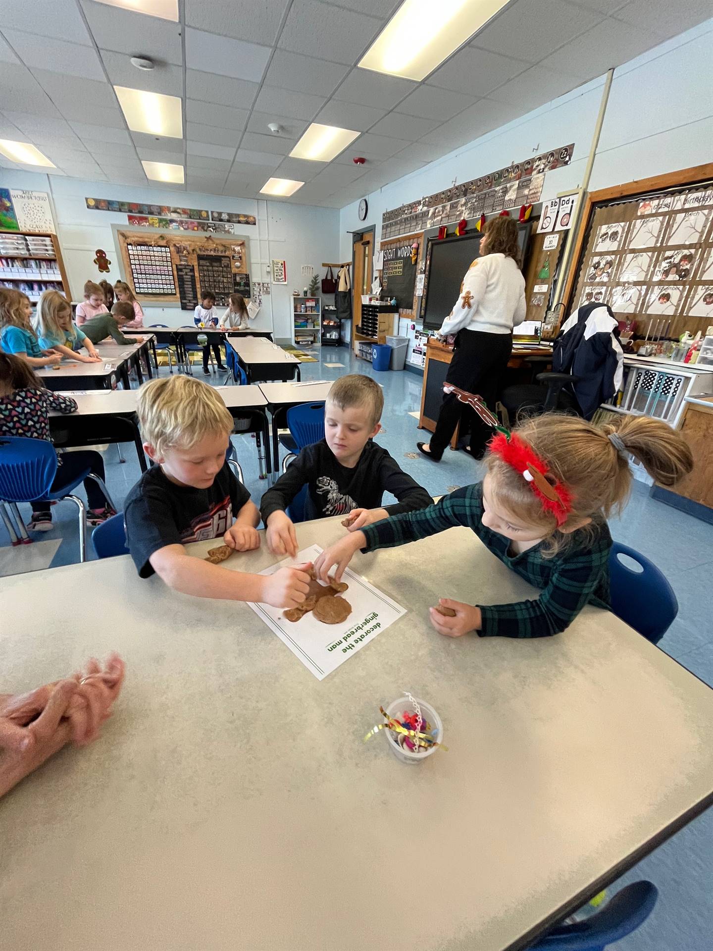 3 students working together to create a play do ginger bread friend.