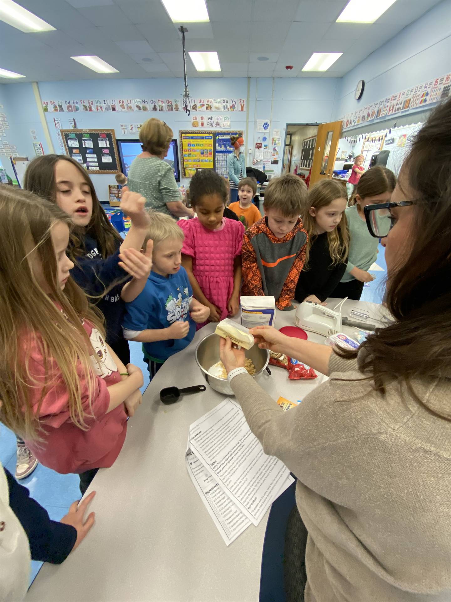 students with teacher mixing cookie ingredients.