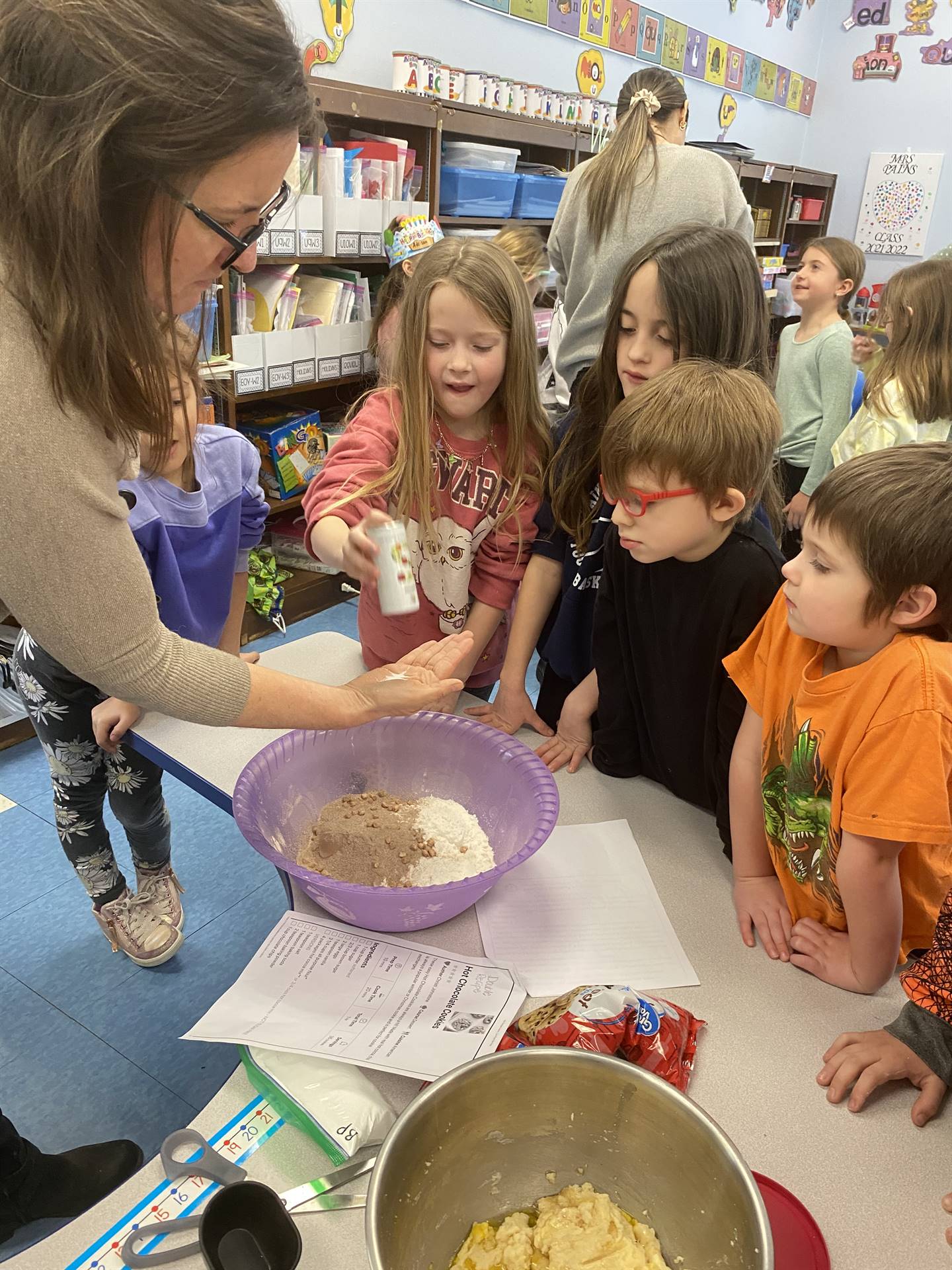 students with teacher mixing cookie ingredients.