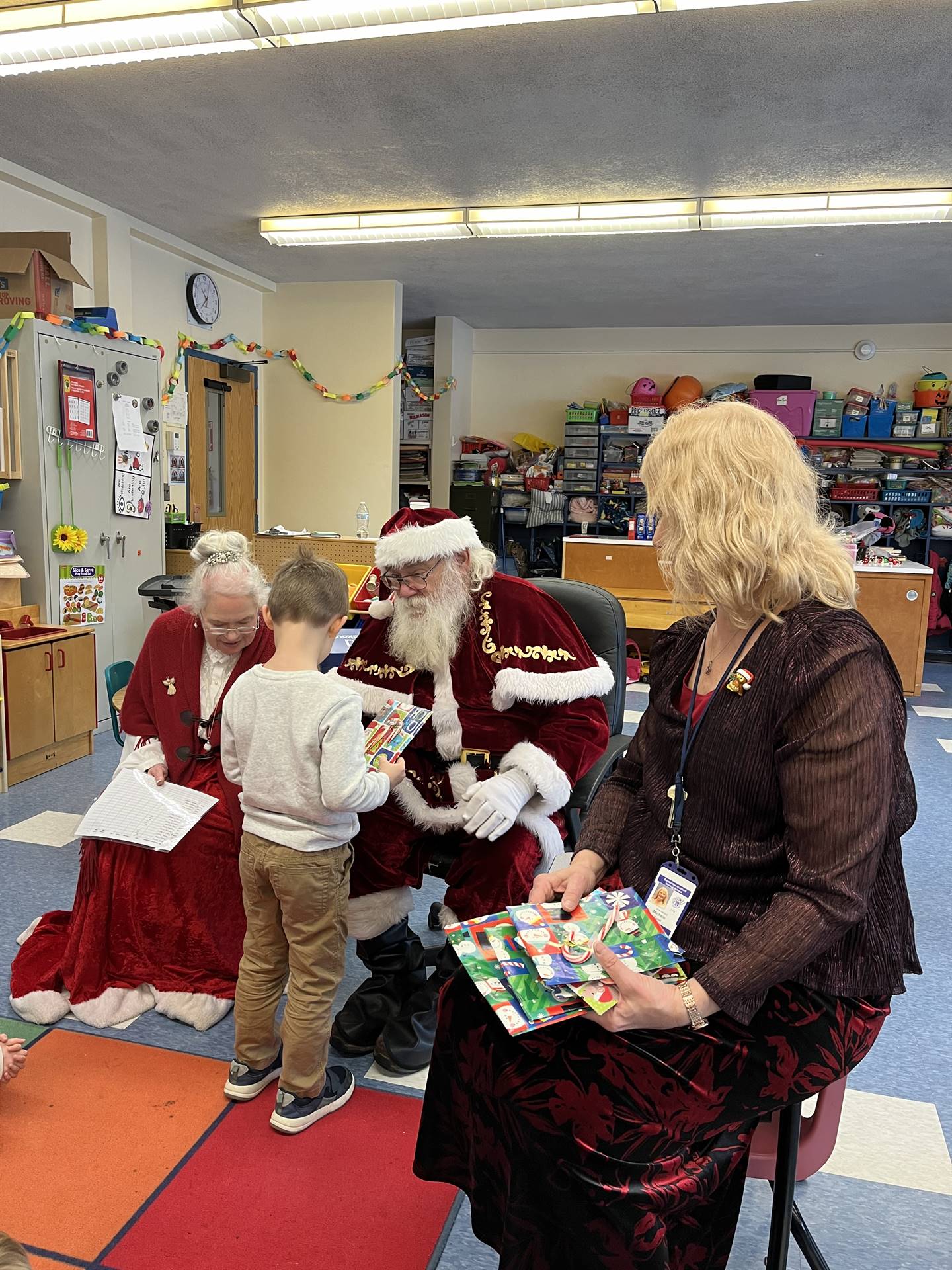 Santa and Mrs. Claus and elf  with student handing out books