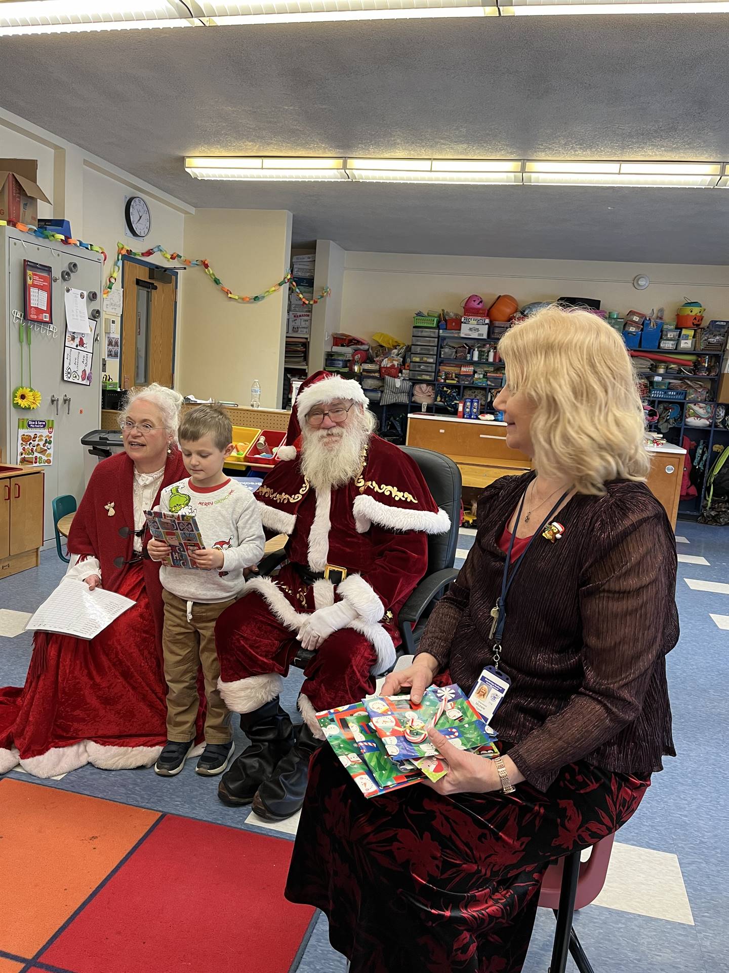 Santa and Mrs. Claus and elf  with student handing out books
