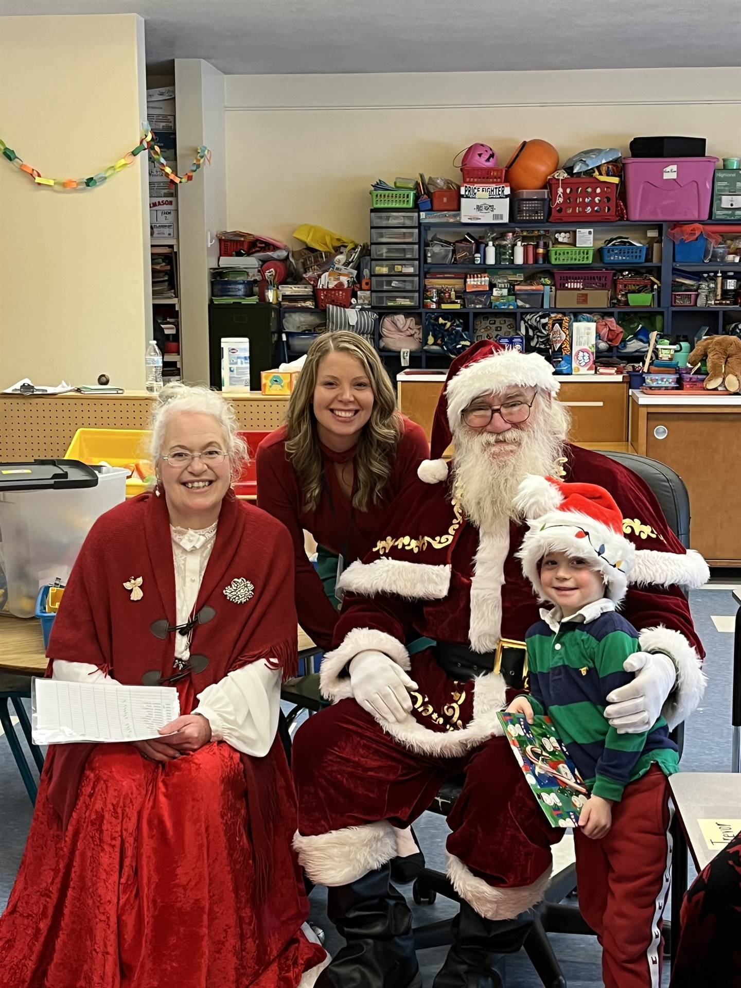 Santa and Mrs. Claus and elf  with student handing out books