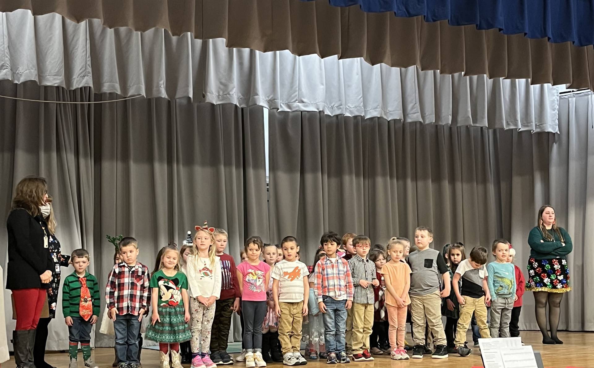 a large group of students on stage with gray curtain background