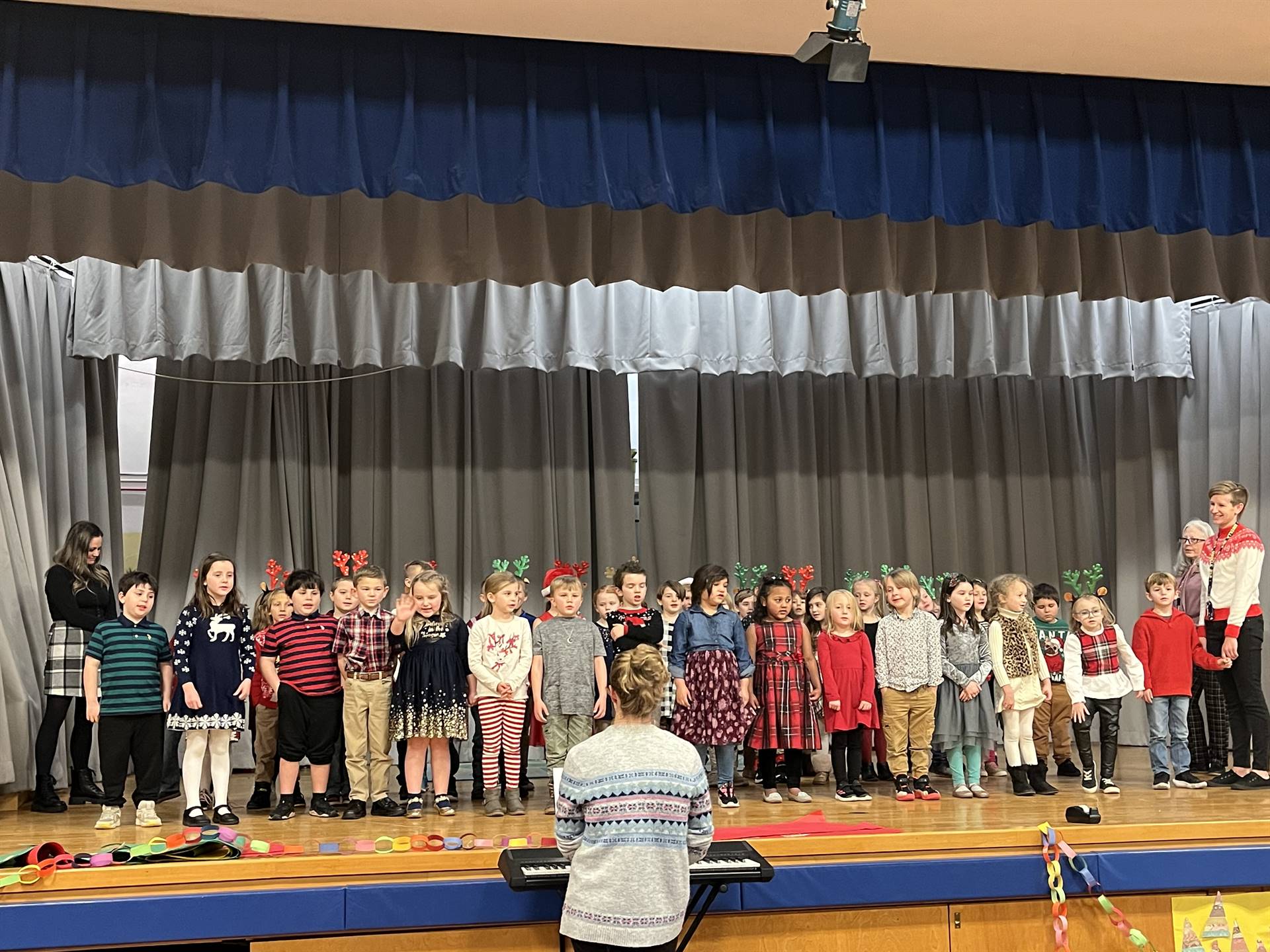 a large group of students on stage with gray curtain background