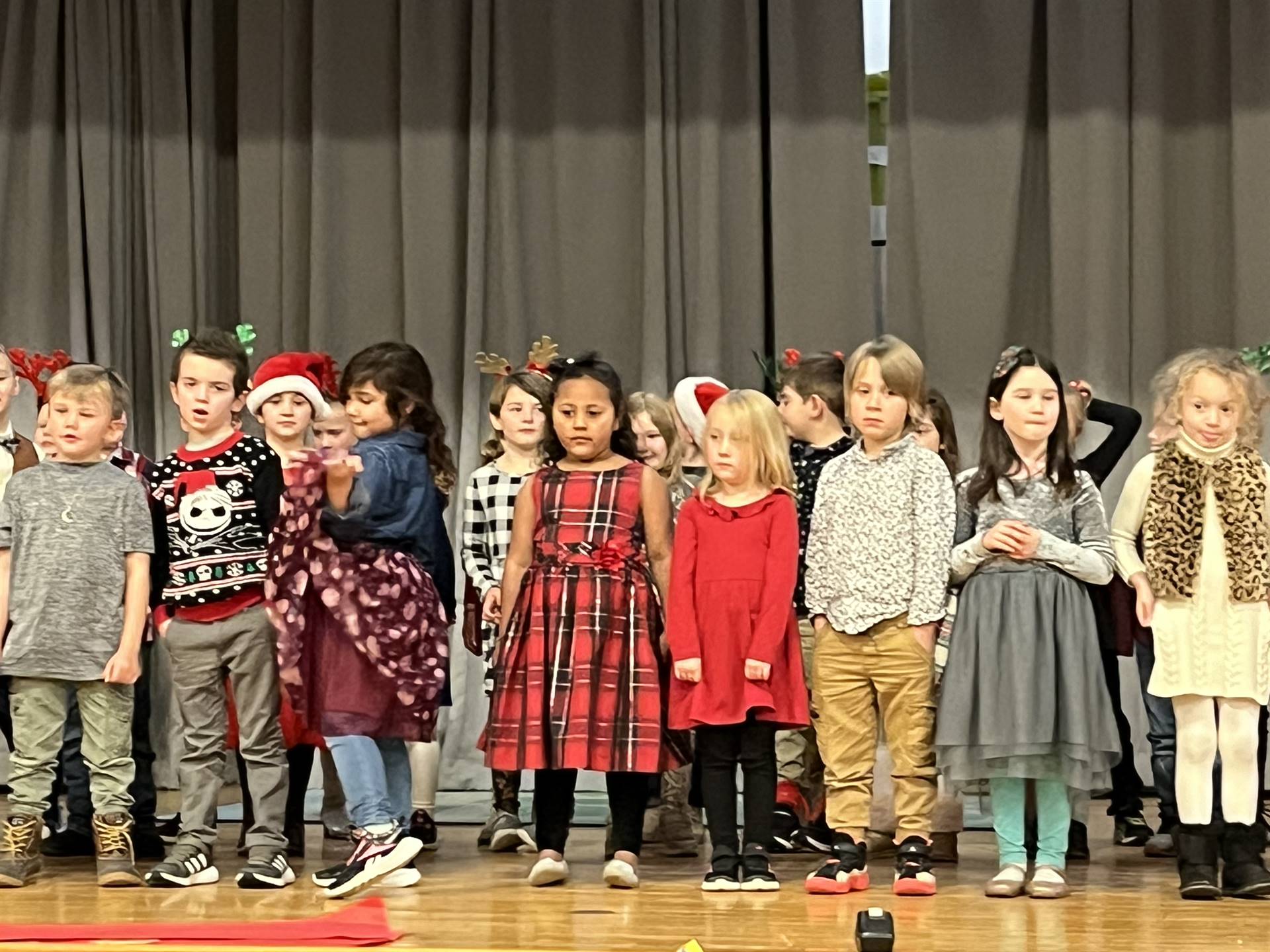 a large group of students on stage with gray curtain background