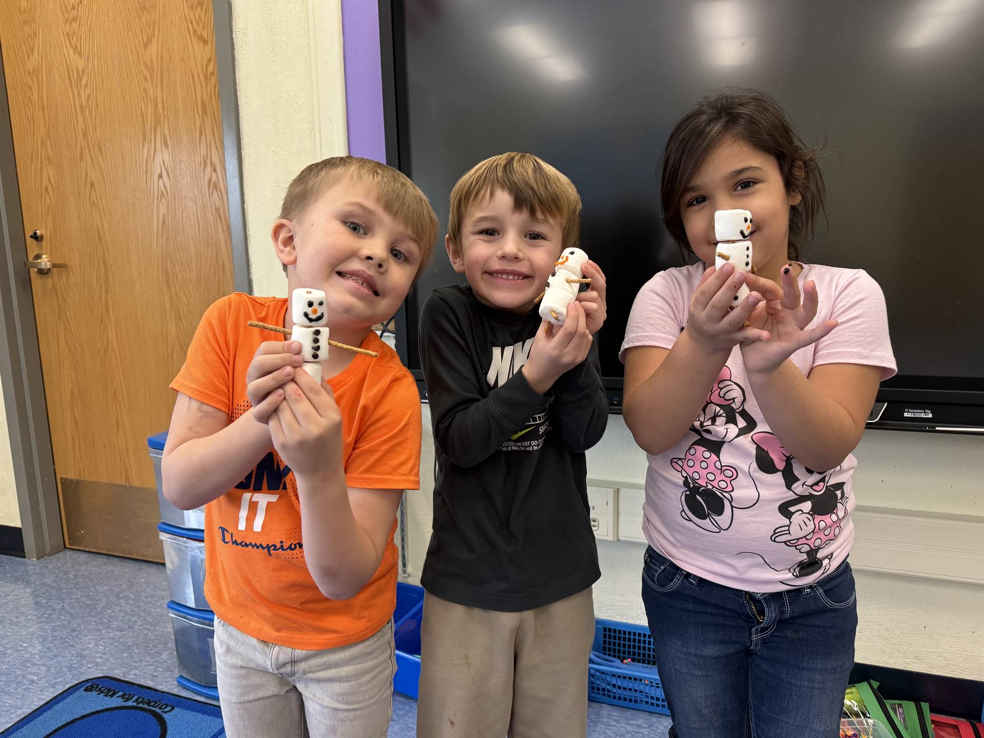 students hold up marshmallow snowmen they made
