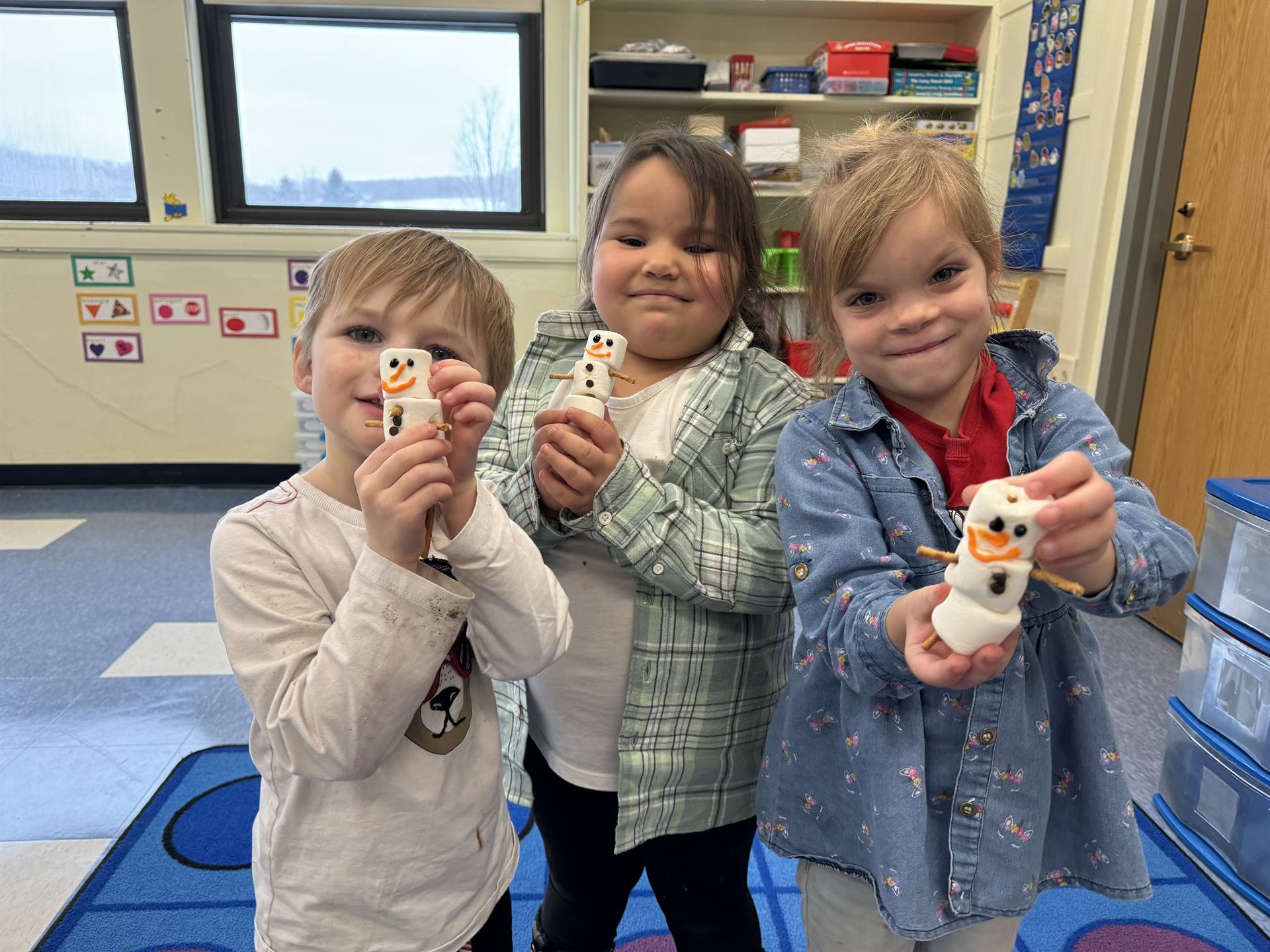 students hold up marshmallow snowmen they made