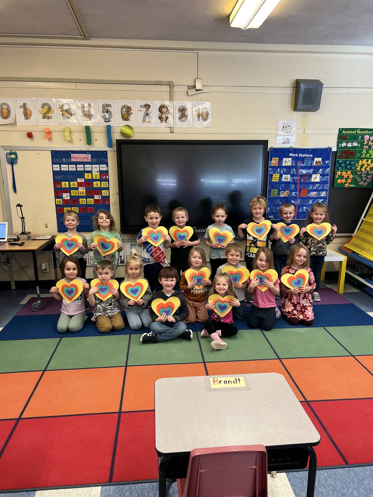 students holding up paper rainbow hearts.