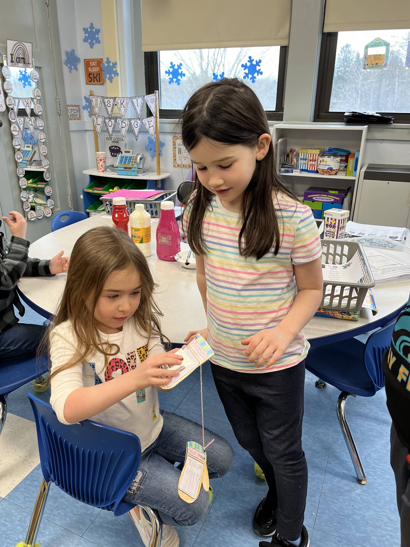 A student hands a paper mitten with a compliment written on it.