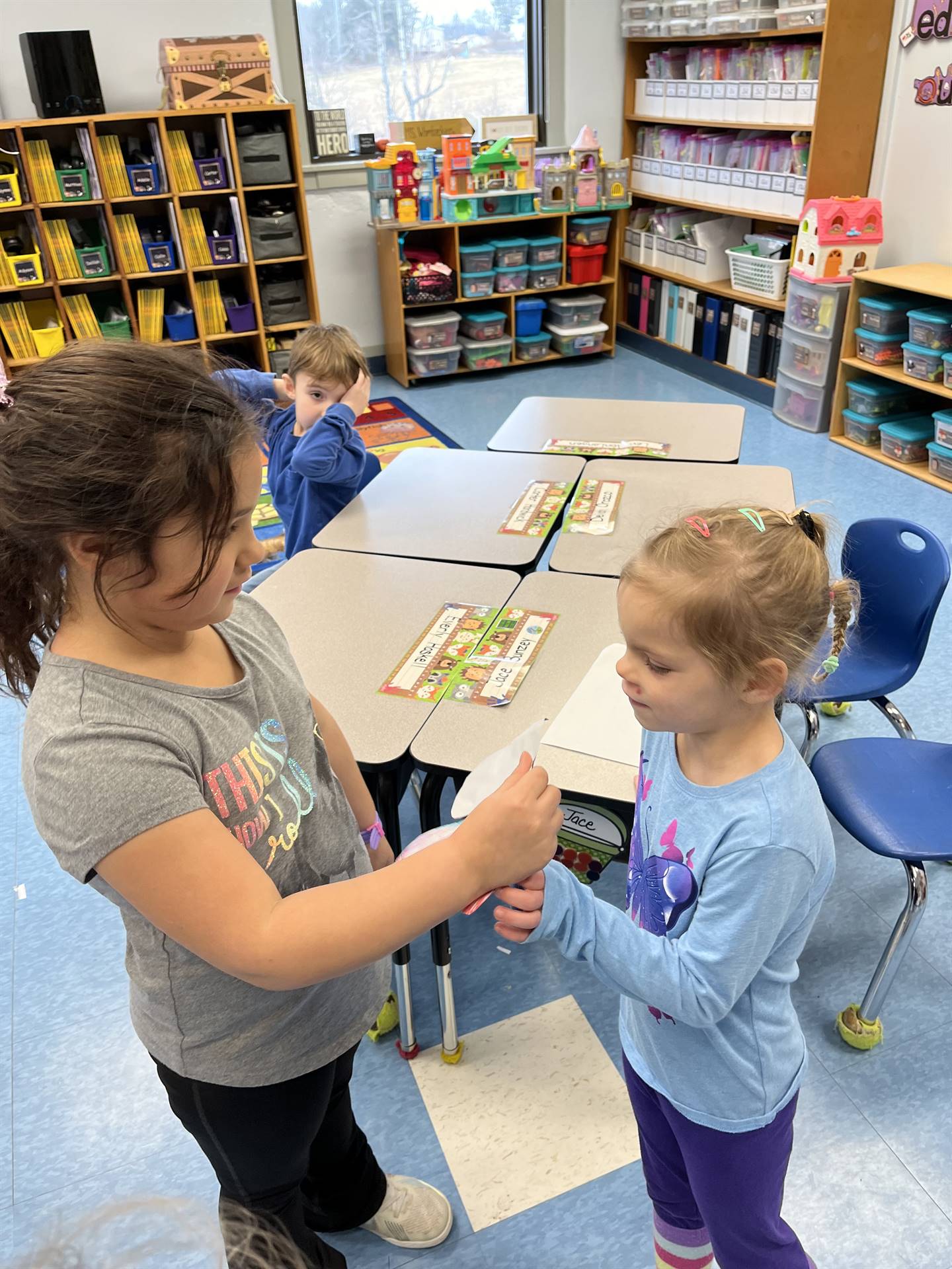 A student hands a paper mitten with a compliment written on it.