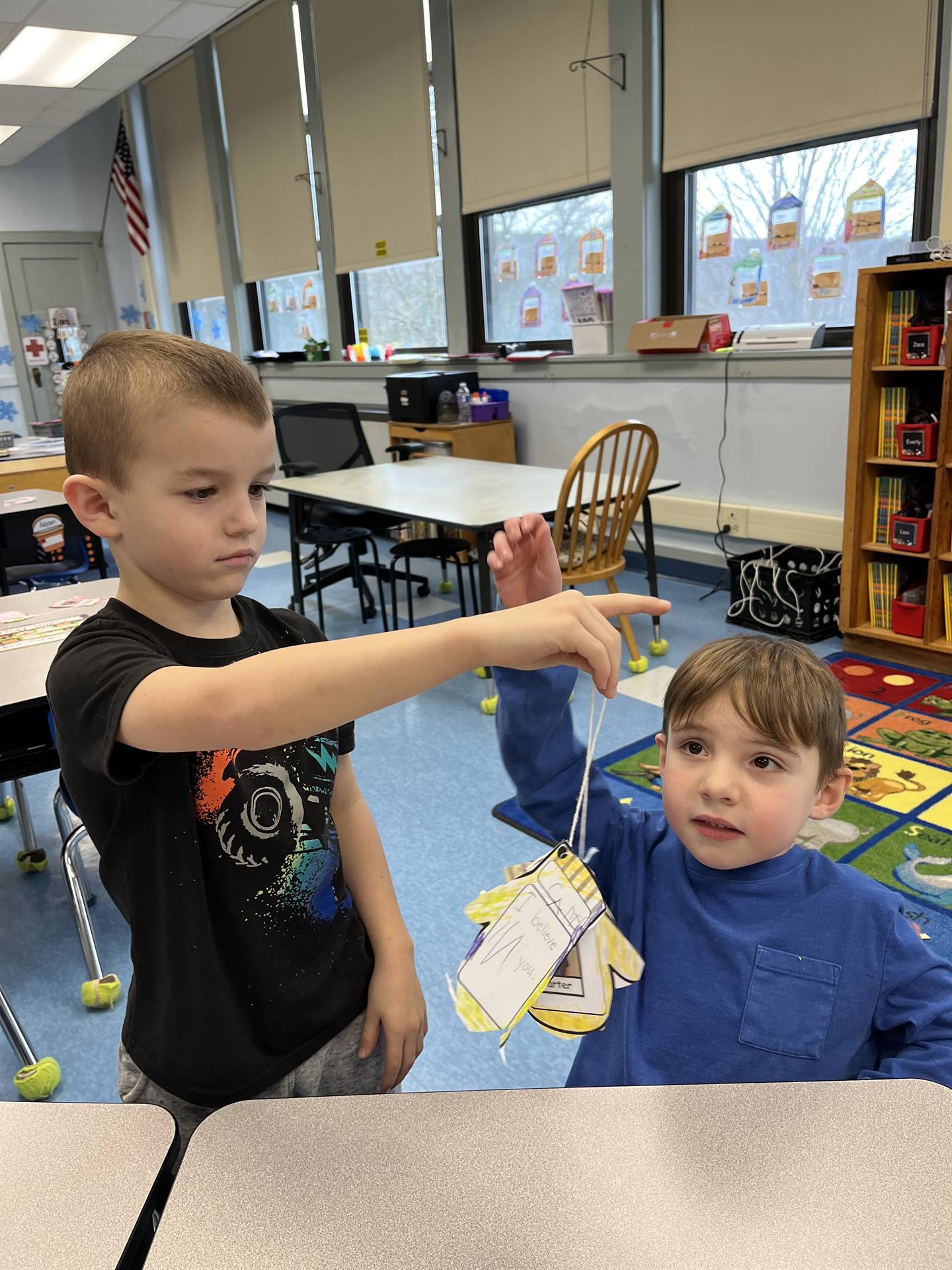 A student hands a paper mitten with a compliment written on it.