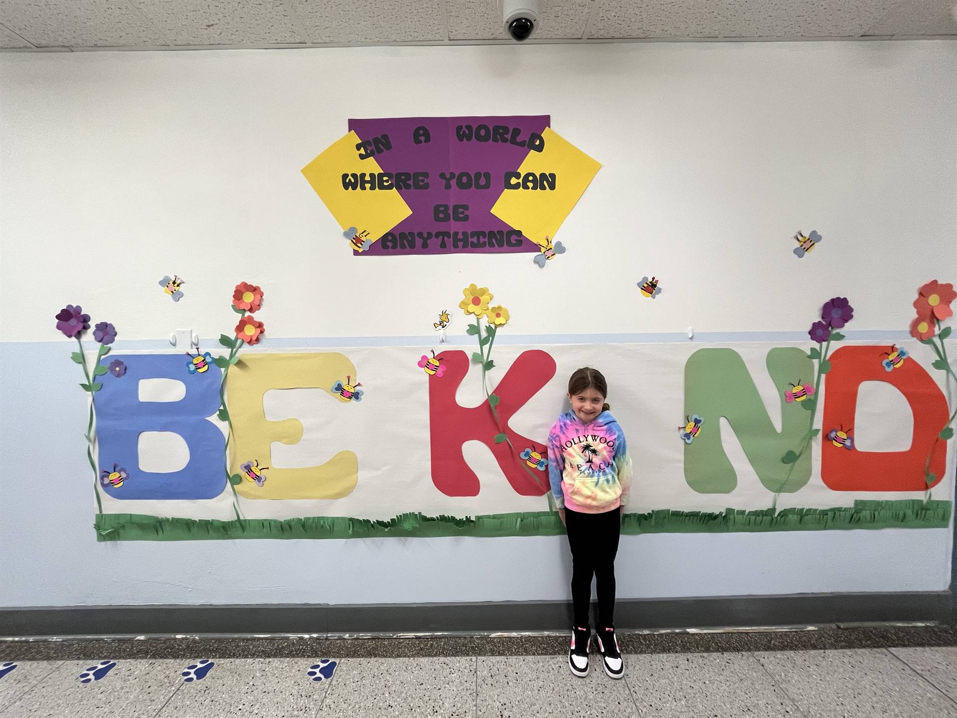 student is "I" in BE KIND poster on wall