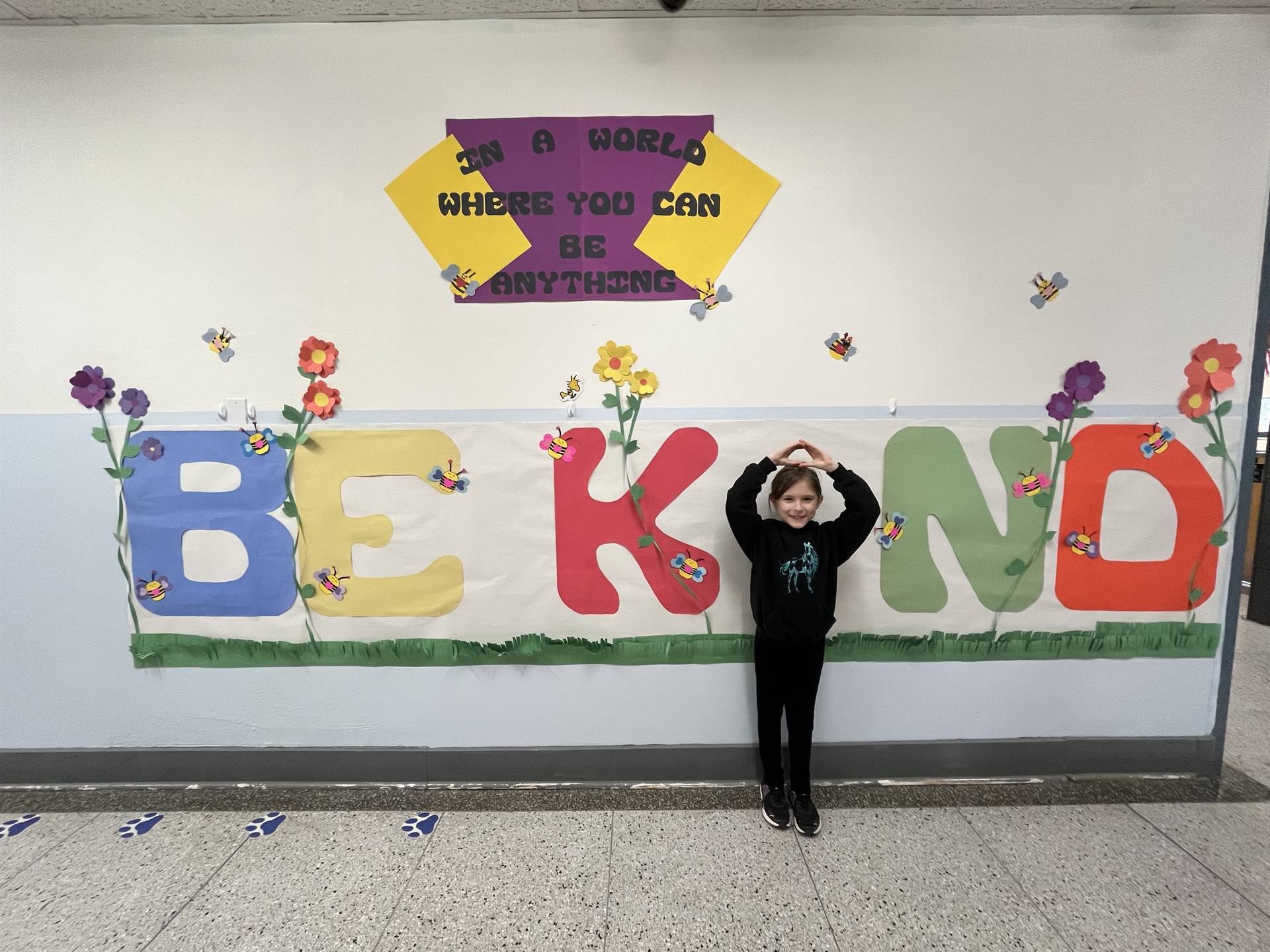 student is "I" in BE KIND poster on wall