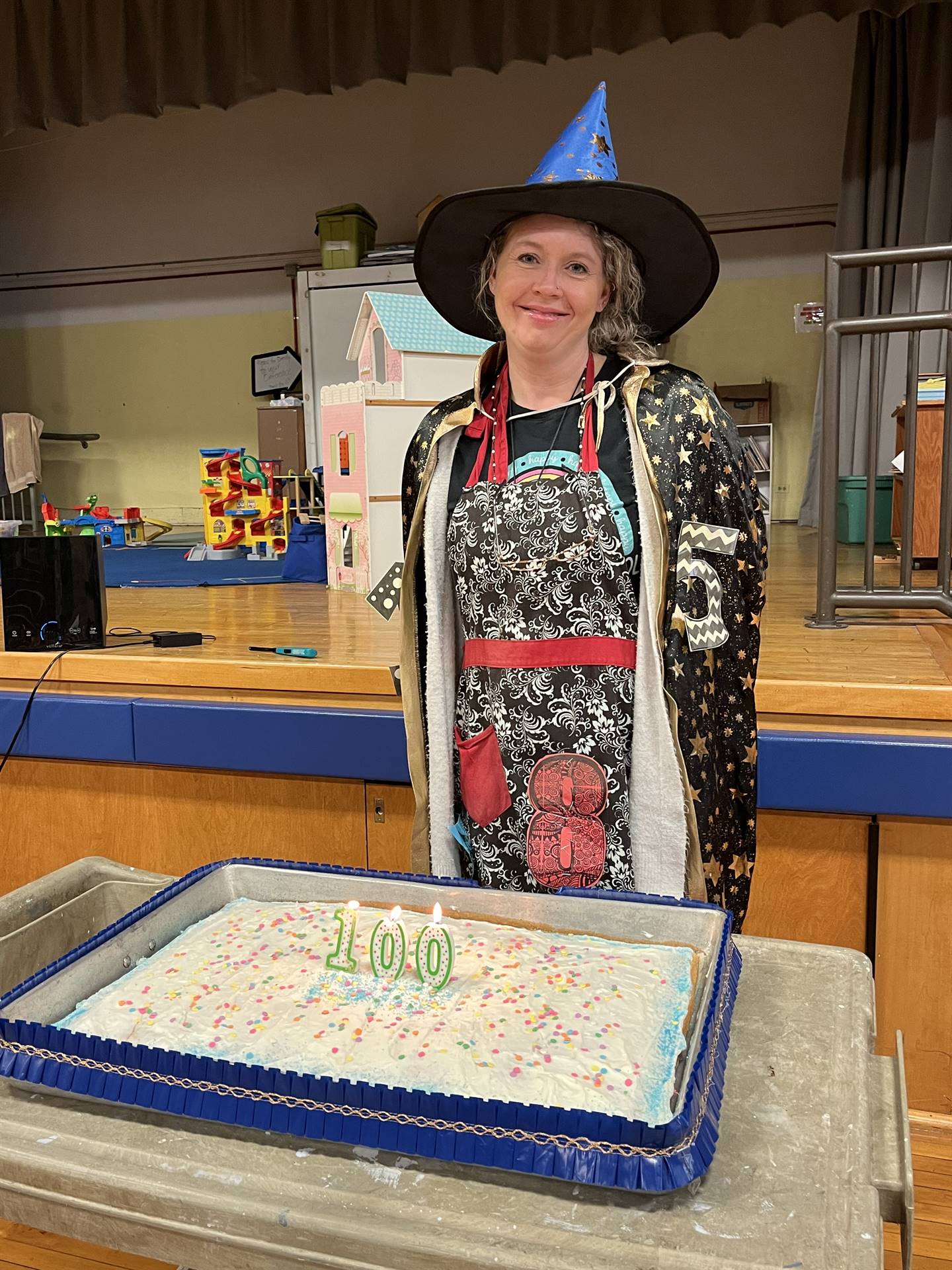 A number wizard next to a cake with 100 candles