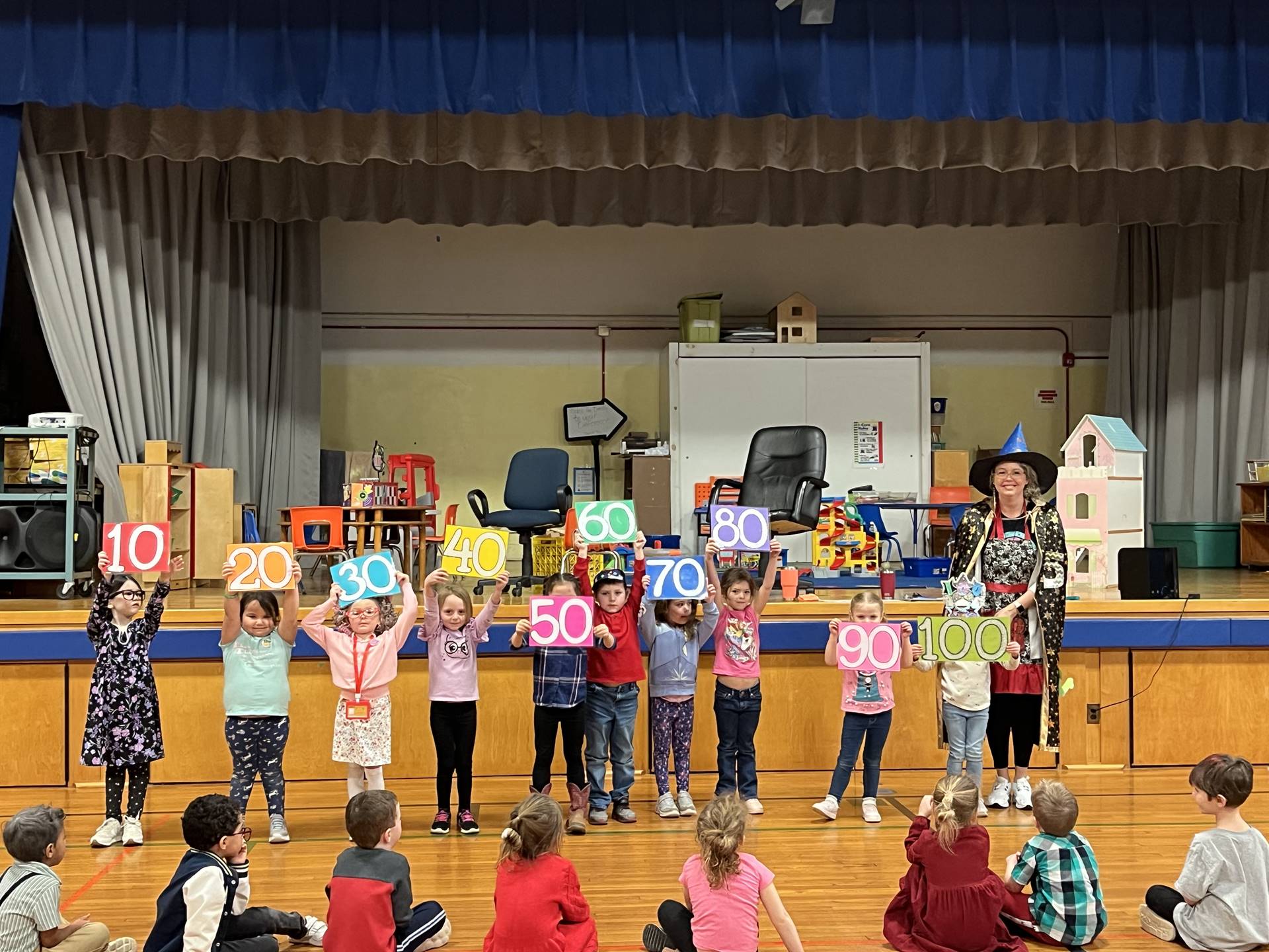 students holding up numbers counting by 10s to 100