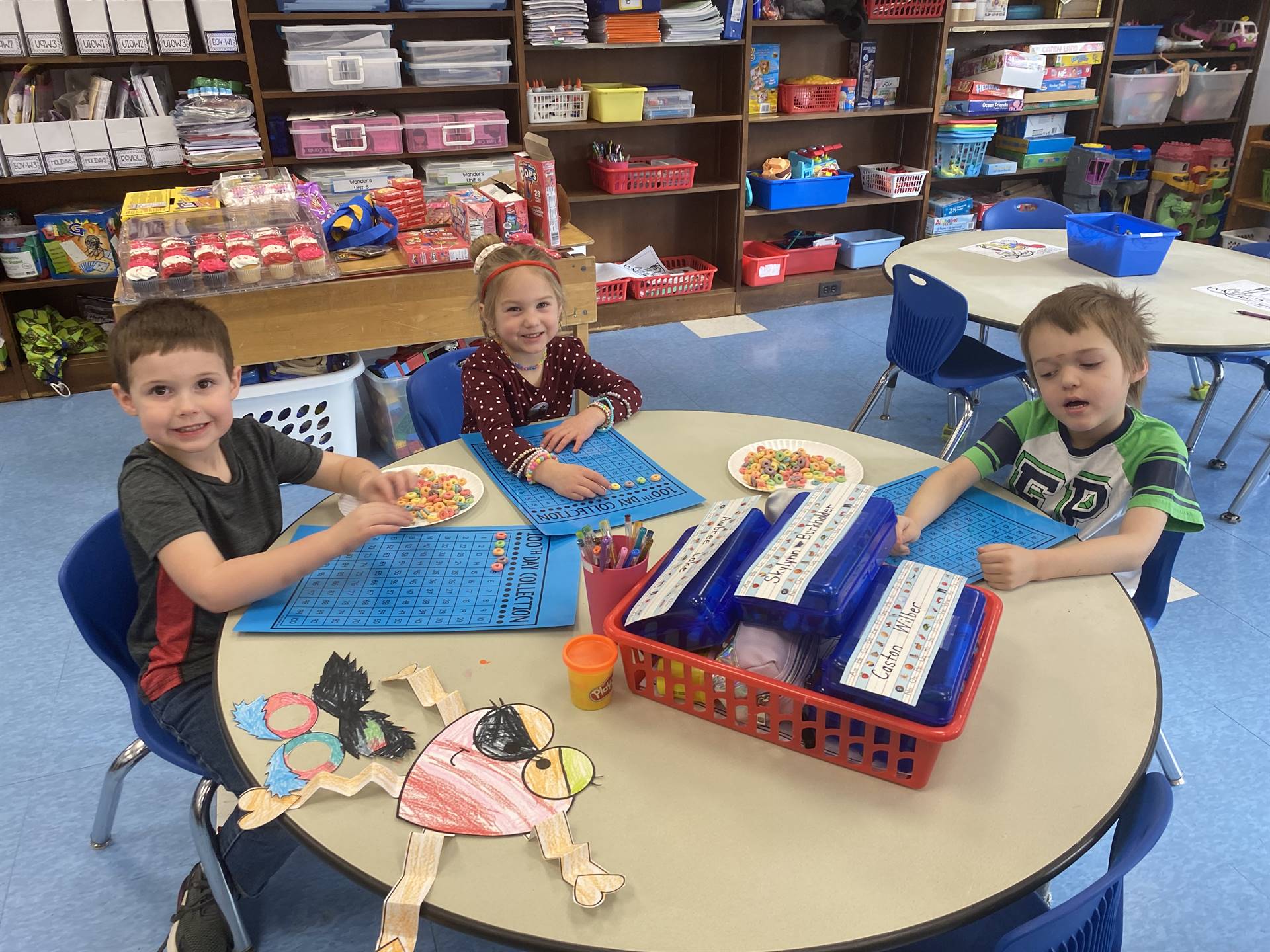 3 students counting fruit loops on a blue counting board