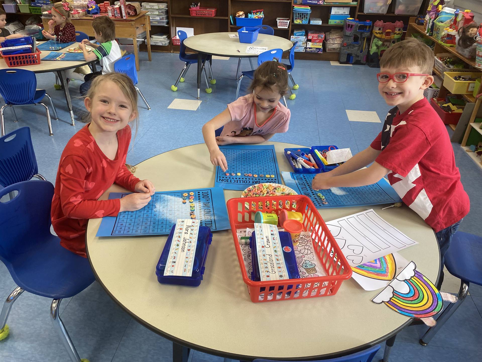 3 students counting fruit loops on a blue counting board