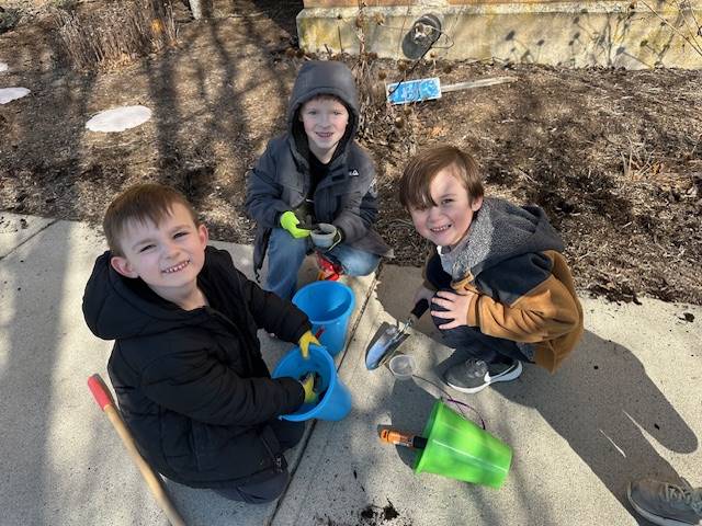 3 students on sidewalk with pails and shovels