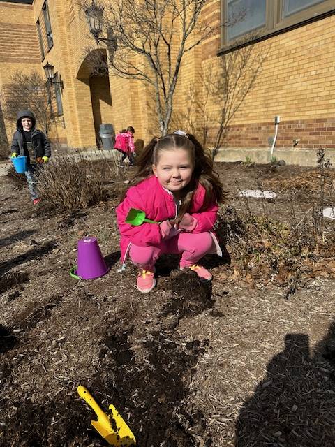 a student on a dirt pile with a shovel