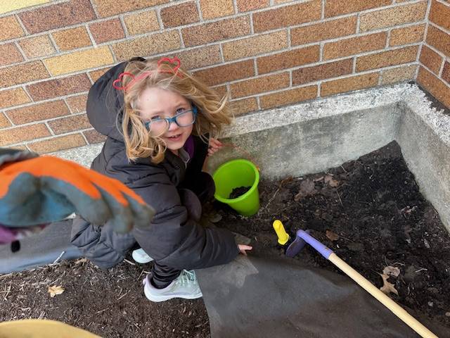 a students with a pail and digging in dirt.