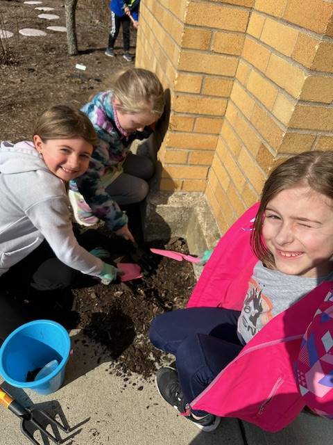 3 students with pails and shovels digging in dirt