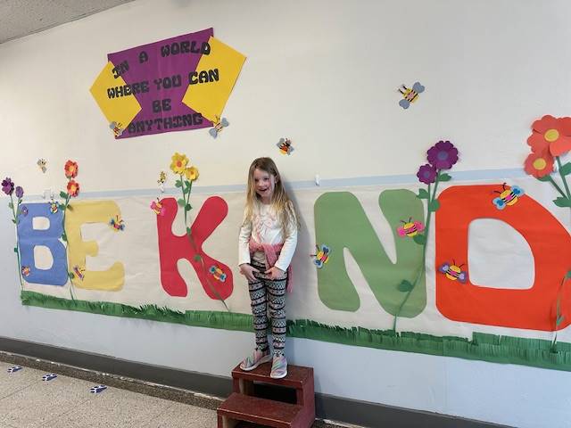 Student standing as "I" in word, "KIND"