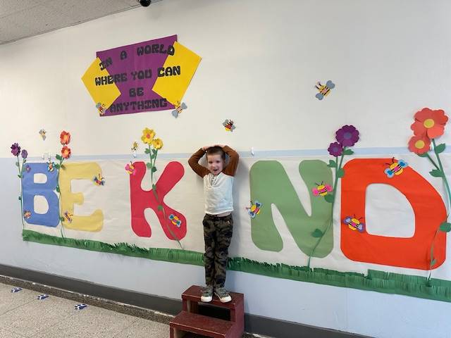 Student standing as "I" in word, "KIND"