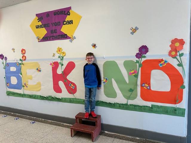 Student standing as "I" in word, "KIND"
