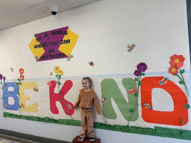 Student standing as "I" in word, "KIND"