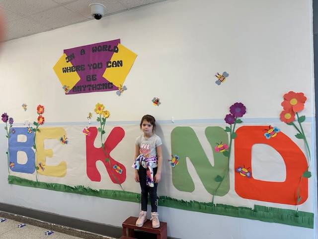 Student standing as "I" in word, "KIND"