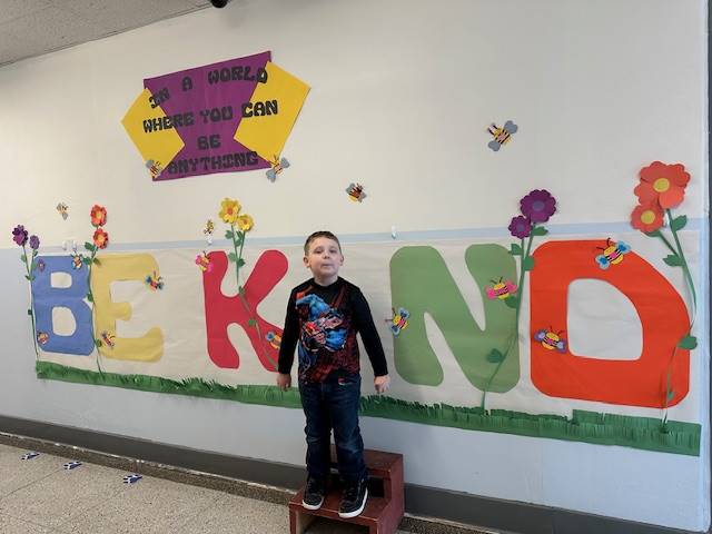 Student standing as "I" in word, "KIND"