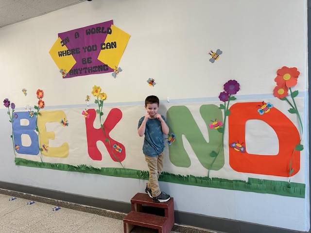 Student standing as "I" in word, "KIND"