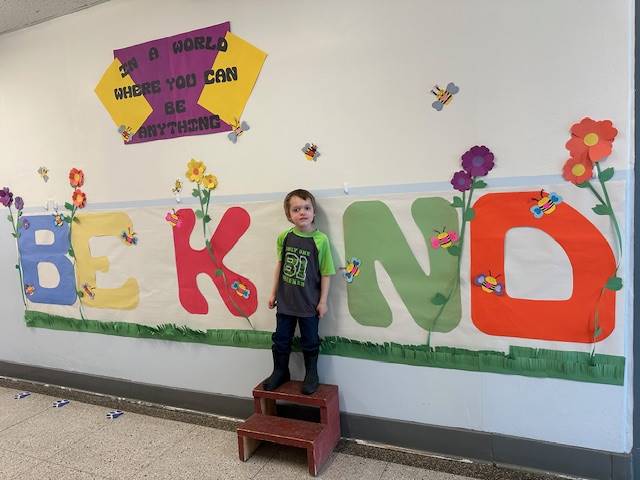 Student standing as "I" in word, "KIND"