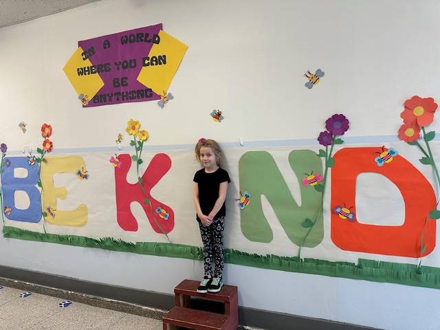 Student standing as "I" in word, "KIND"