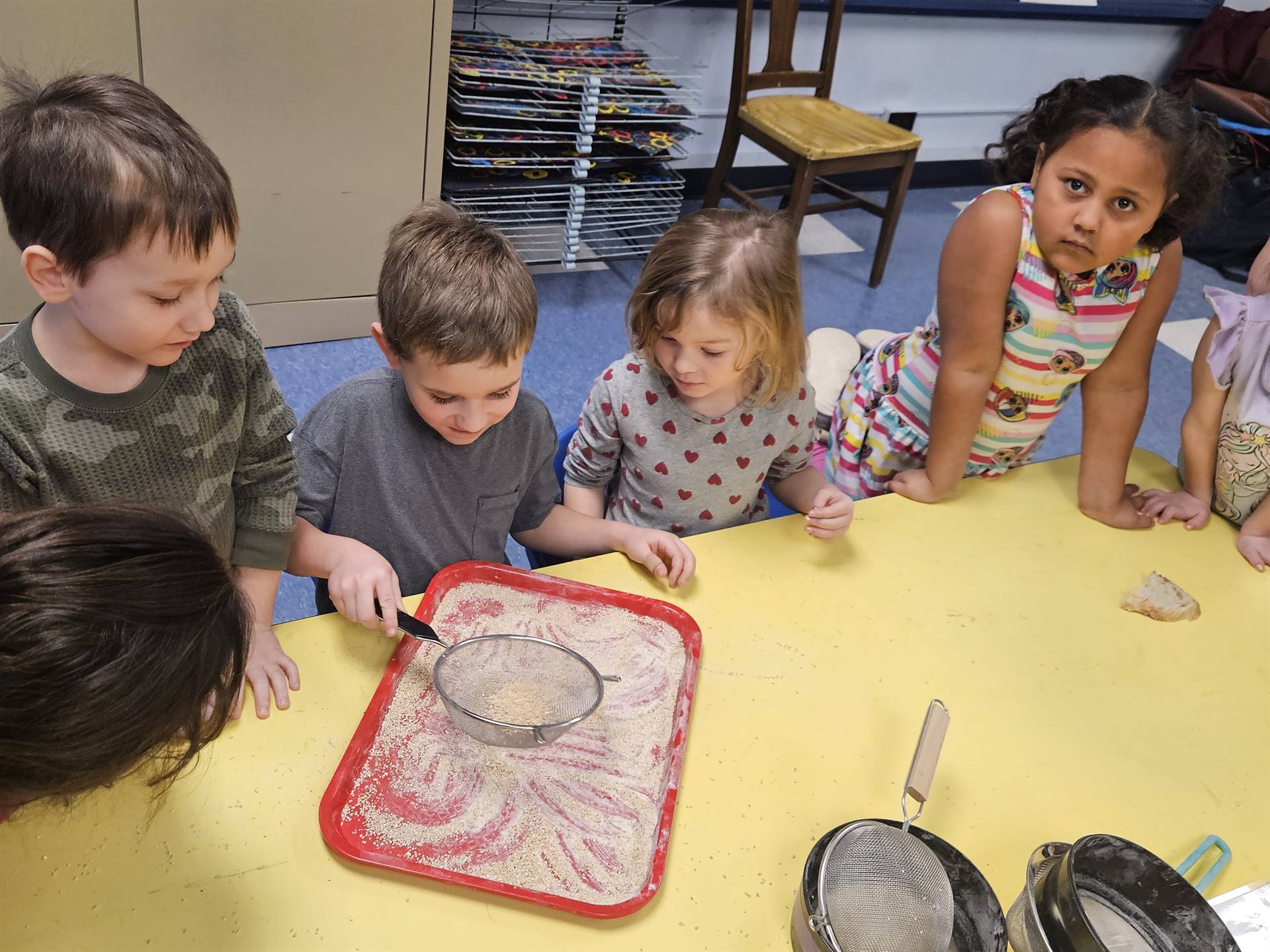 4 kids take turns sifting flour.